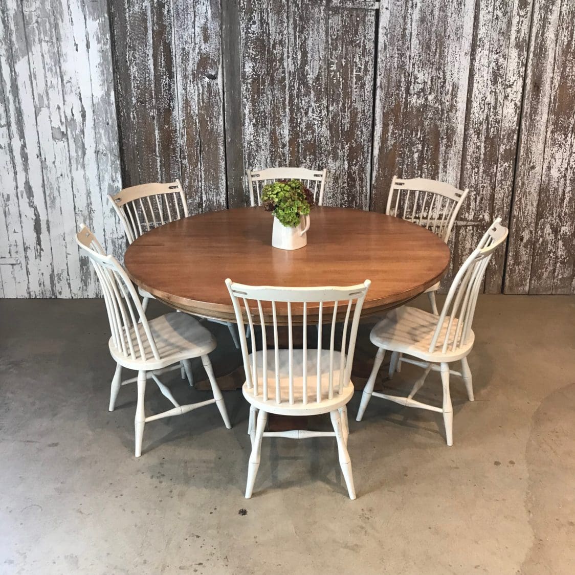 Round pedestal table in maple wood in light finish with white chairs